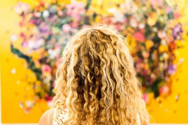 Девушка с кудрявыми волосами смотрит на разноцветные бумажки
