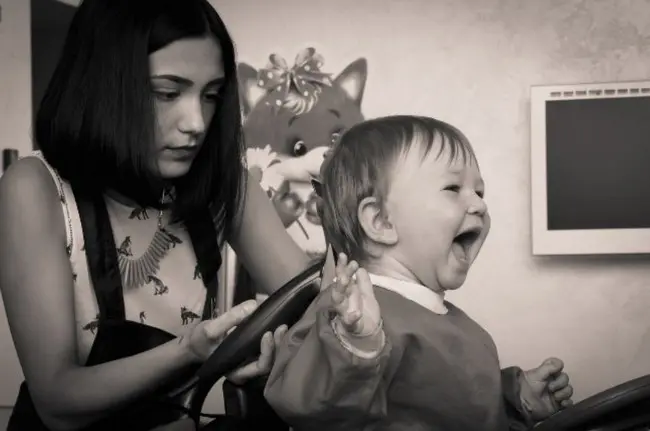 Симпатичная девушка АСМР - парикмахер делает машинкой стрижку ребенку