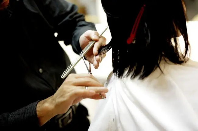 Парикмахер делает АСМР стрижку девушке с темными волосами